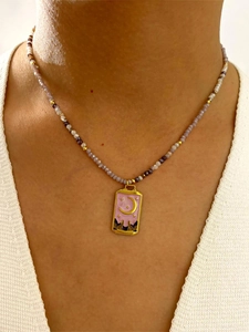 Détail d'un collier de perles bohème avec pendentif lune en émail rose sur modèle