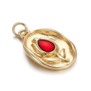 Macro detail of a gold-plated oval locket with tulip relief and a red stone center