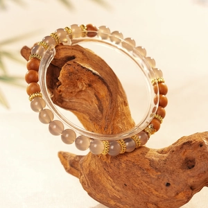 Détail des perles de bois de santal et d'agate grise sur un support en bois naturel