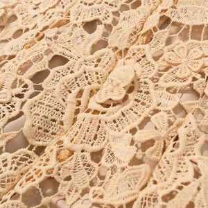Detailed macro view of the intricate beige floral lace texture and silky lining fabric