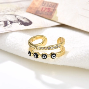 Golden double-layer evil eye ring with sparkling crystals on white fabric background