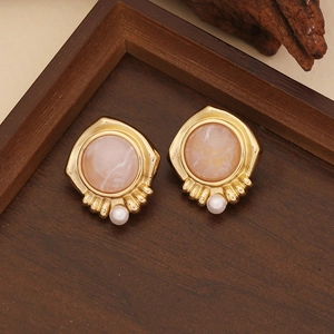 Macro view of vintage gold flower earrings with pink textured inlay and a white pearl drop