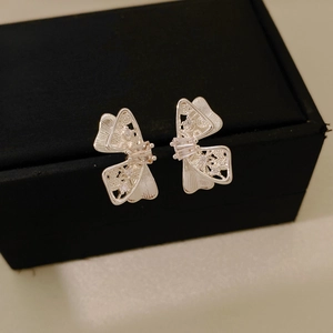 Détail de boucles d'oreilles nœud en argent avec design ajouré et pierres zircons