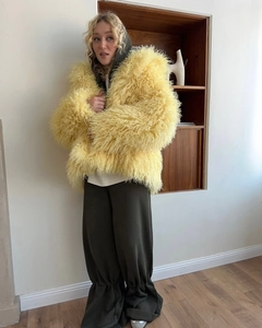 Detail of the oversized faux fur coat in pale yellow with a long fluffy texture finish