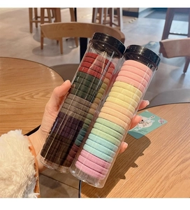 Detail of multi-color elastic hair bands set in two transparent cylinder storage tubes