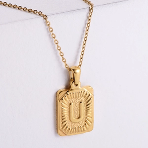 Detail of 18K gold plated stainless steel rectangle pendant with embossed letter U