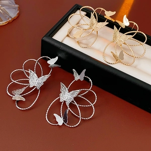 Detailed view of hollow butterfly earrings in gold and silver finish on display