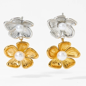 Makro-Detail von zweifarbigen Blumenohrringen mit Perlen auf gold- und silbernem Edelstahl