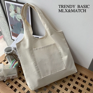 Detail of minimalist cream canvas tote bag with front pocket on wooden table