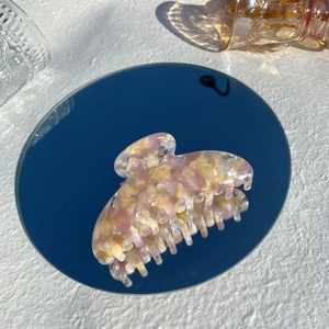Macro shot of large pink marble acetate hair claw clip showing polished resin texture