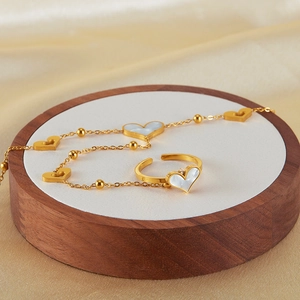 Detailed close-up of gold-tone heart necklace and ring set with white mother of pearl inlay