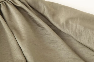 Close-up of olive green satin fabric with metallic luster on a bomber jacket
