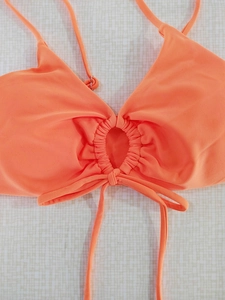 Detail of orange halter bikini top featuring center ring ruching and adjustable ties