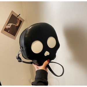 Detail of the black skull cross-body bag featuring white round eyes and heart-shaped nose