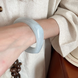 Detail of a wide light blue marble texture resin bangle on a model's wrist with Zen style