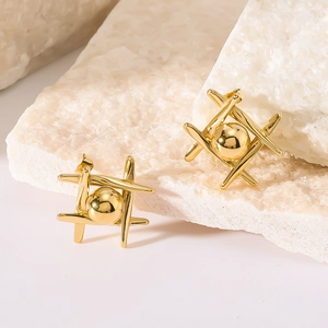 Geometric gold ball earrings in a grid structure on white textured stone background