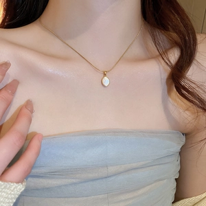 Gros plan d'un collier doré avec pendentif ovale en nacre sur le cou d'un mannequin