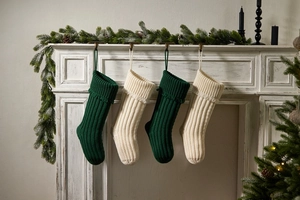Close-up of knit Christmas stockings in cream and dark green hanging on a white fireplace