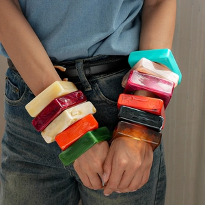 Macro detail of square acrylic resin bangles with colorful marble texture on female wrist