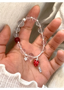 Close-up of glass bead bracelet with red strawberry charm and silver engraved tag