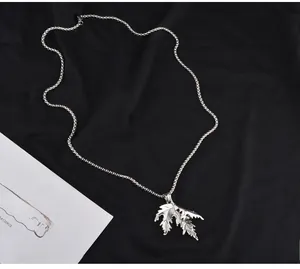 Détail d'un pendentif feuille d'érable en acier titane argenté sur une chaîne à billes