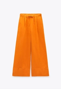 Detail einer leuchtend orangefarbenen Weithals-Hose mit elastischem Kordelzug am Bund