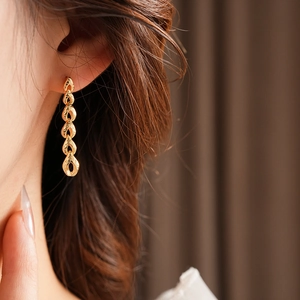Gros plan d'élégantes boucles d'oreilles dorées avec chaîne à maillons ovales évidés