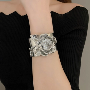 Macro shot of polished silver liquid flower cuff bracelet with detailed petals on model