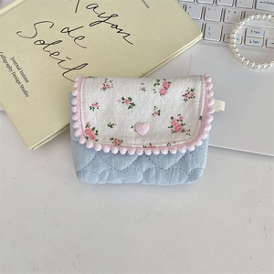 Detail of floral quilted fabric storage pouch with pink pom-poms and a heart button