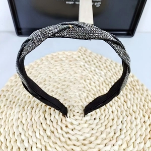 Close-up of a braided headband with dark sparkling rhinestones on a woven mat