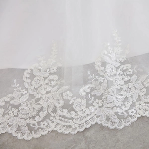 Detailed close-up of intricate white lace floral embroidery on long wedding dress train