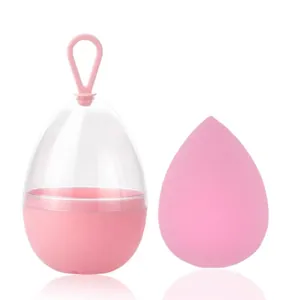Roze druppelvormige make-up spons met een draagbare transparante opbergdoos en ring