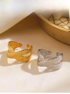 Detail of gold and silver crisscross rings with textured geometric lines on silk fabric