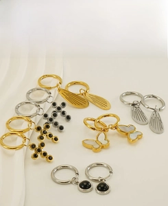 Macro shot of gold and silver stainless steel earrings with butterfly and cross charms