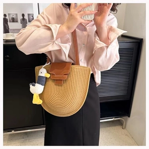 Detail of beige woven cotton bag featuring a brown leather flap and cute duck pendant