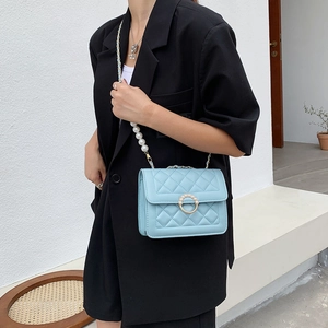 Light blue quilted crossbody bag with pearl strap and metal buckle on a model