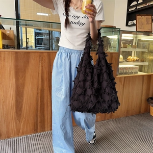 Close-up of a large black fringe tote bag with layered tassels for a textured casual look