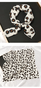 Détail d'un foulard carré en soie avec motif marguerite orange sur tissu de lin blanc