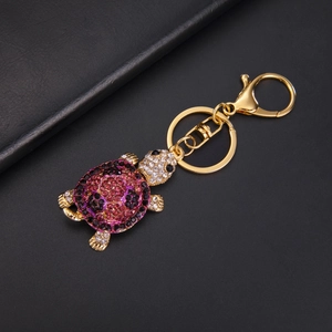 Detail of golden turtle keychain featuring vibrant purple and clear sparkling rhinestones