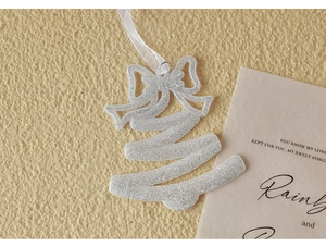 Silver glitter Christmas tree ornament with elegant white ribbon on textured background