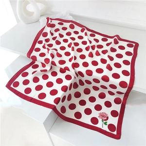 Detailed shot of white silk scarf with red polka dots and delicate pink rose flower