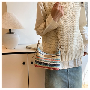 Detail of colorful rainbow striped woven shoulder bag with slim leather strap on model