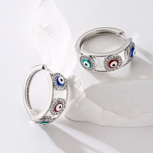 Silver evil eye hoop earrings with blue red and green zircon stones on stone background