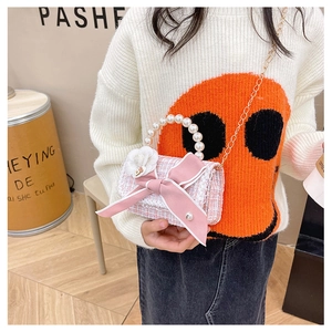 Pink tweed cross-body girl's bag with bow and pearl handle shown on a young model