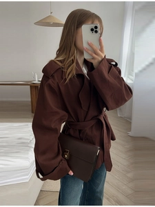Dettaglio del trench corto marrone scuro con revers e cintura regolabile in vita coordinata