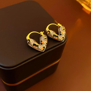 Macro view of gold-plated leopard print heart hoop earrings on a jewelry box