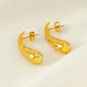 Close-up of gold teardrop earrings featuring sparkling clear pavé diamonds and sleek finish