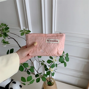 Close-up of pink jacquard cosmetic bag with floral texture and brand woven label