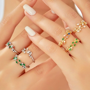 Detailed view of adjustable leaf rings with green and clear gemstones in gold and silver