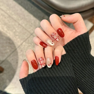 Close-up of red checkerboard press-on nails with 3D cherry accents and silver shimmer